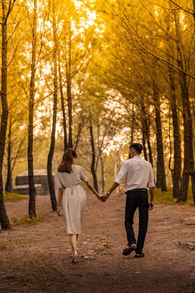 Couple holding hands walking down the woods.